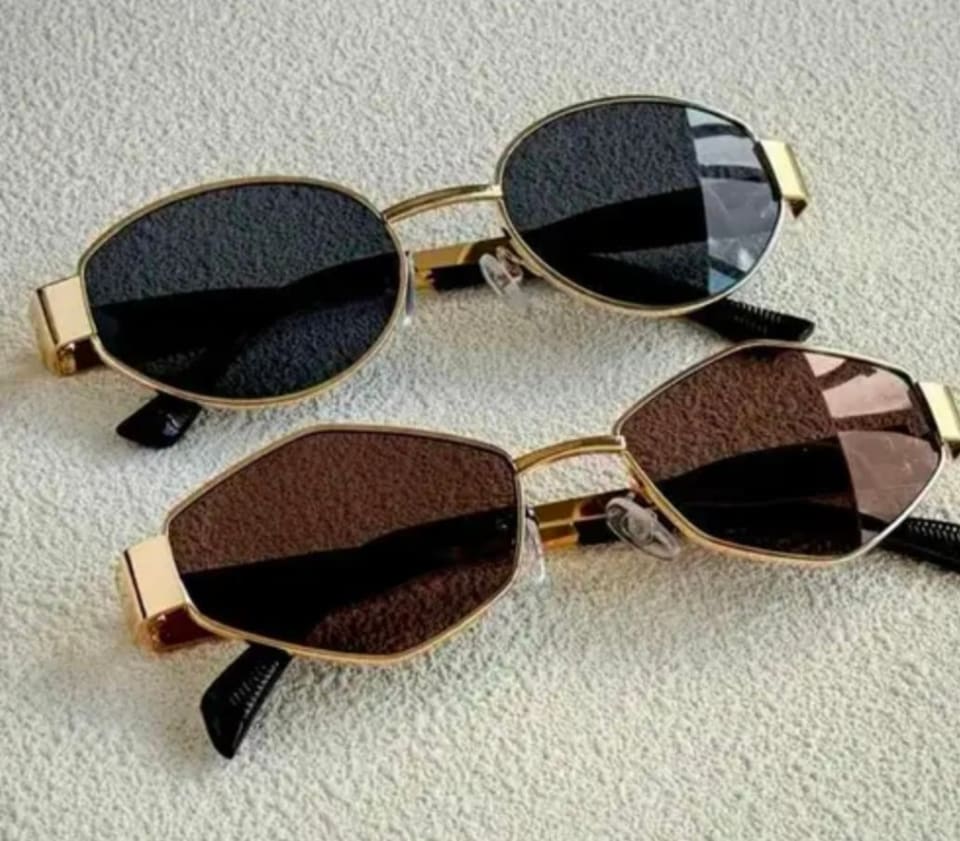 Two pairs of SK Style 01 sunglasses with gold rims and dark lenses on a light surface