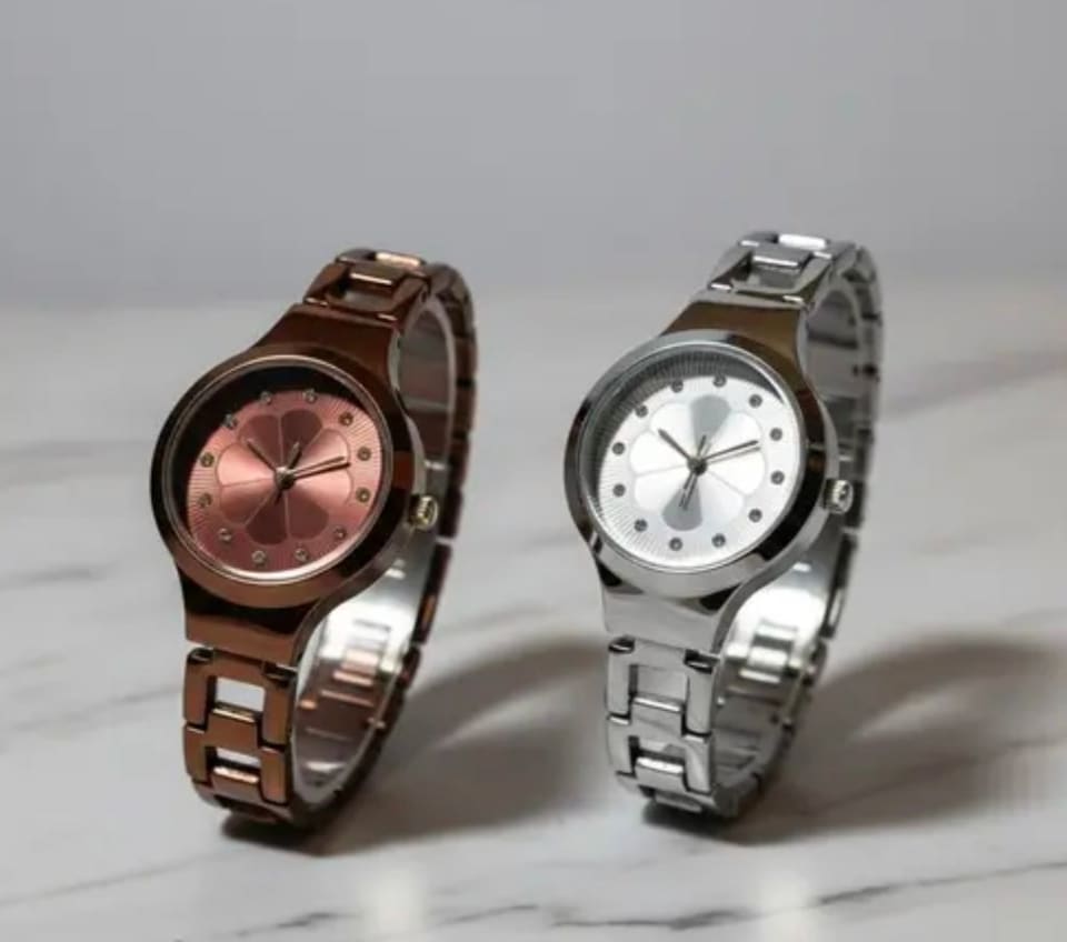 Bronze and silver watches side by side on a marble surface